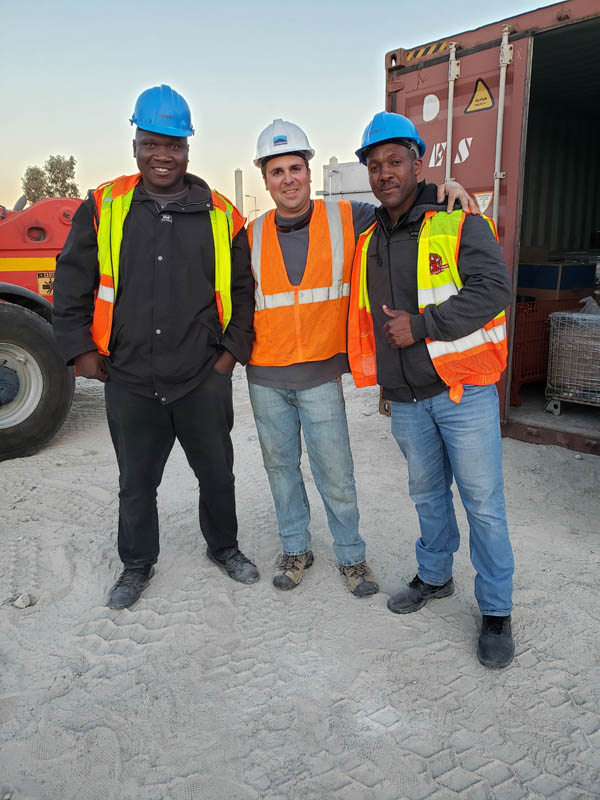 three men in safety vests and hard hats posing outdoors