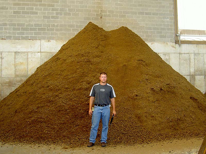 Man standing in front of pile of animal bedding, a bi-product of the two-stage linear vortex digester