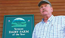 mitch moorlag next to a sign that says "dairy farm of the year"